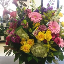 Large mixed bouquet in a black vase with pink, yellow, purple, and white flowers