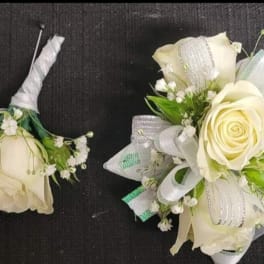 Two white rose boutonnieres with ribbon and baby's breath