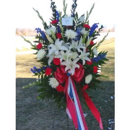 Large standing floral spray with white lilies, red carnations, and blue accents