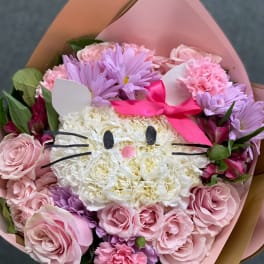 Pink and lavender bouquet with a cat-face flower center and ribbon