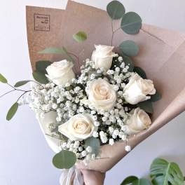 Bouquet of white roses with baby's breath and eucalyptus in brown paper
