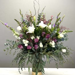 Tall floral arrangement with white lilies and pink roses in a gold vase