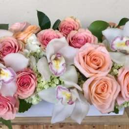 Pink and peach roses with white orchids in a white rectangular box