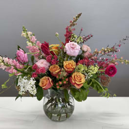 Mixed bouquet of pink and orange flowers in a clear glass vase