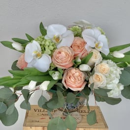 Peach roses and white orchids in a glass vase
