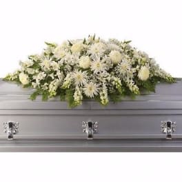 White floral casket spray with green accents on a gray casket