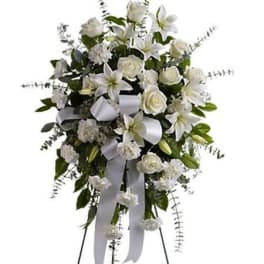 White floral standing spray with lilies, roses, and ribbon