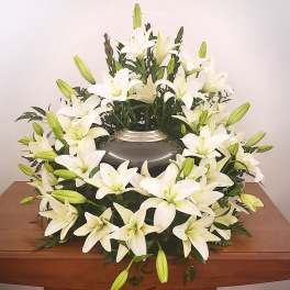 White lily funeral wreath around a dark urn
