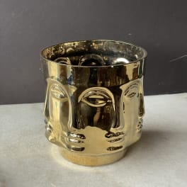 Gold metallic decorative candle holder with a face design