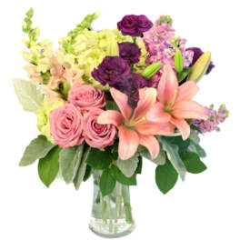Pink roses and lilies in a clear glass vase with purple and yellow flowers