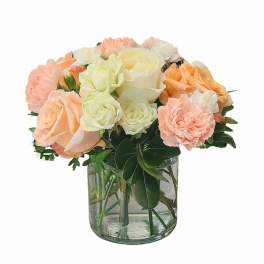 Peach and white roses with carnations in a clear glass vase