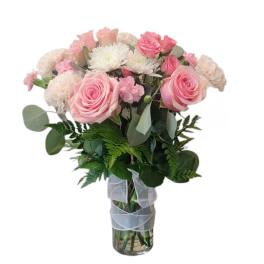 Pink roses and white flowers in a clear glass vase with ribbon