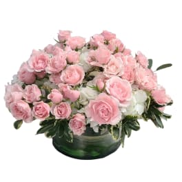 Pink roses arranged in a low green glass bowl with white flowers