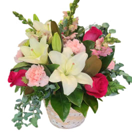 Basket arrangement of white lilies, pink roses, and carnations