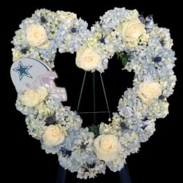 Heart-shaped floral wreath with pale blue and white flowers and cream roses