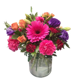 Mixed bouquet of pink, purple, and orange flowers in a glass vase