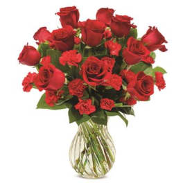 Bouquet of red roses and red carnations in a clear glass vase