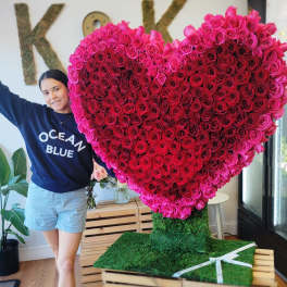 Large heart-shaped rose display with a person standing beside it