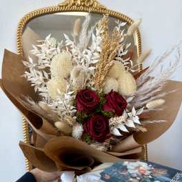 Bouquet of red roses with dried beige grasses and white foliage