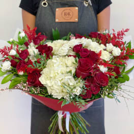 Large bouquet of red roses and white hydrangeas wrapped in red paper