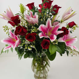 Red roses and pink lilies arranged in a clear glass vase