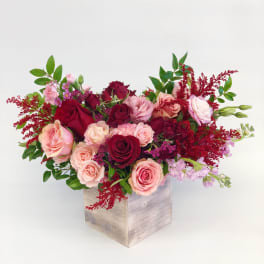 Pink and burgundy roses arranged in a wooden box