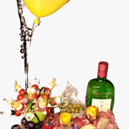 Gift tray with a yellow balloon, liquor bottle, cupcakes, and assorted snacks