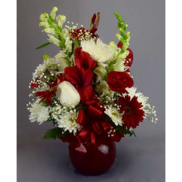 Red and white mixed flower arrangement in a red vase with a ribbon