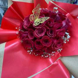 Bouquet of deep pink roses wrapped in bright red paper with a butterfly topper
