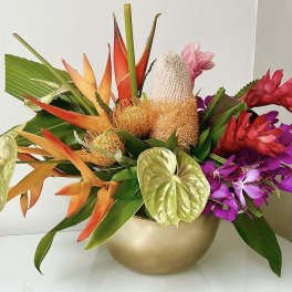 Tropical flower arrangement in a gold bowl with orange, red, pink, and purple blooms