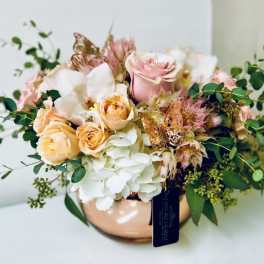 Bouquet of pink and peach roses with white hydrangeas in a copper vase