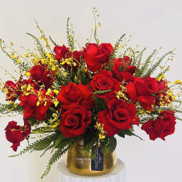 Red roses with yellow accents in a gold vase