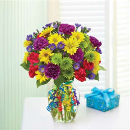 Colorful mixed bouquet in a glass vase with a gift box nearby
