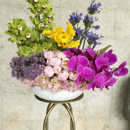 Colorful floral arrangement with orchids, calla lilies, peonies, and hydrangeas in a white bowl