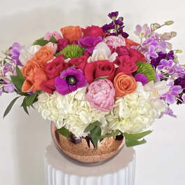Bright mixed bouquet in a copper vase with pink, orange, white, and purple flowers