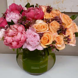 Pink and peach roses with peonies in a green glass vase
