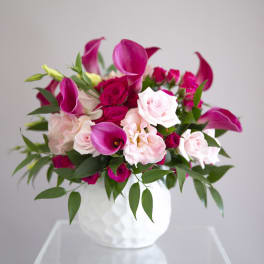 Pink and white roses with magenta calla lilies in a white vase