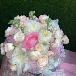 Round bouquet of pale pink and white flowers with a bright pink center bloom