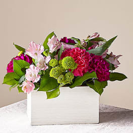 Pink and magenta flowers arranged in a white rectangular box