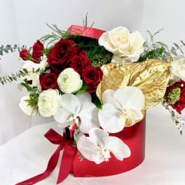 Bouquet of red and white roses with white orchids in a red box