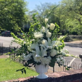 White floral arrangement in a white pedestal vase outdoors