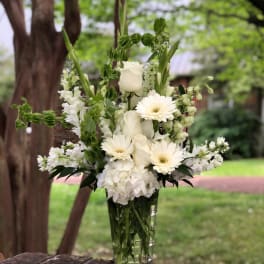White roses and daisies arranged in a clear glass vase