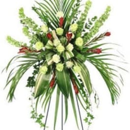 Standing floral spray with green foliage, pale blooms, and red accents on an easel