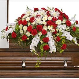 Red and white floral spray on a wooden casket