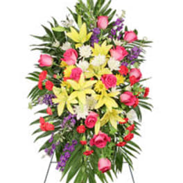 Standing floral spray with pink roses, yellow lilies, and purple accents