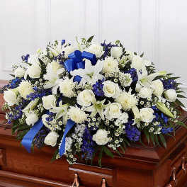 White and blue floral casket spray with roses and lilies