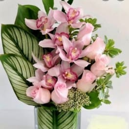Pink orchids and roses arranged in a clear glass vase