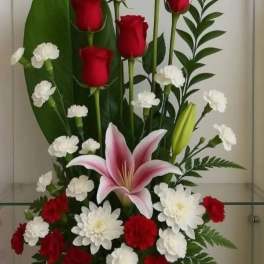 Red roses, white carnations, and a pink lily in a black vase