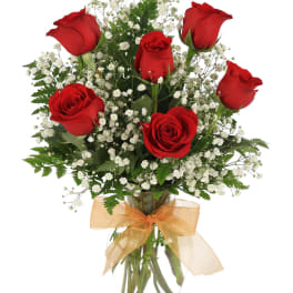 Red roses with white baby's breath in a glass vase with a gold bow
