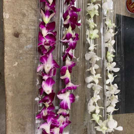Clear plastic trays holding purple and white orchid garlands
